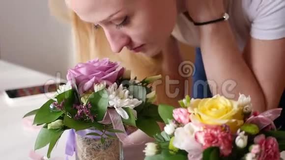 年轻漂亮的女孩正在小花瓶里闻着美丽而明亮的小花抚摸着树叶4K视频的预览图