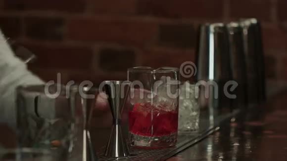 在酒吧里工作的专业酒保把冰和酒混合在玻璃里喝视频的预览图