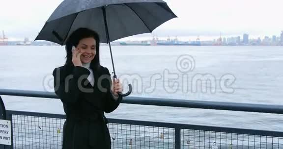 女人拿着伞用手机说话视频的预览图