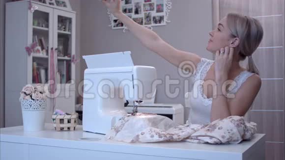 年轻女子坐在缝纫机旁用手机自拍视频的预览图