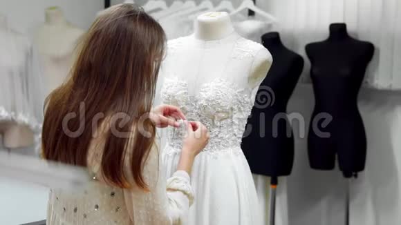 一个女孩在一件穿着一件连衣裙上用独家订购的缝纫面料和莱茵石制作婚纱的肖像视频的预览图
