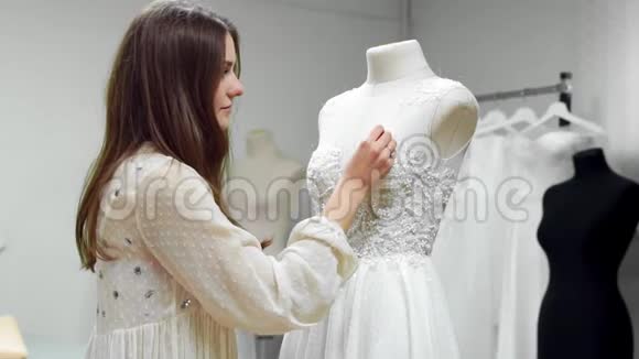 一个女孩在一件穿着一件连衣裙上用独家订购的缝纫面料和莱茵石制作婚纱的肖像视频的预览图