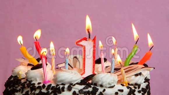一周年纪念日蛋糕和蜡烛放在粉红色背景上视频的预览图
