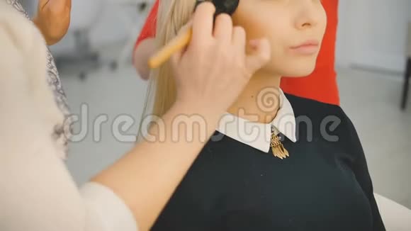 专业化妆师的特写镜头将化妆应用于美丽的年轻性感模特的脸上视频的预览图