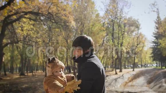 幸福的家庭爸爸在秋天的落叶公园里把孩子扔上去散步视频的预览图