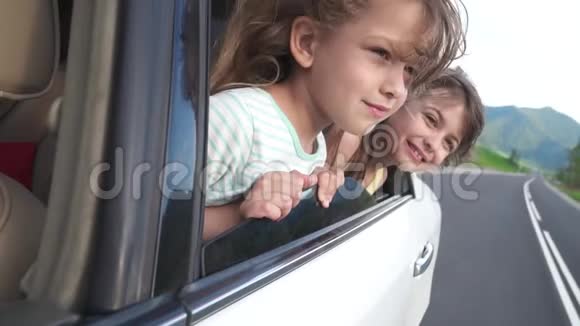 无忧无虑的孩子们探出车窗微笑着两个小女孩在车里玩得很开心慢动作视频的预览图