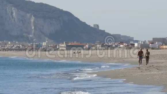 年轻的一对夫妇走在地中海沿岸背景是直布罗陀岩笼罩着视频的预览图