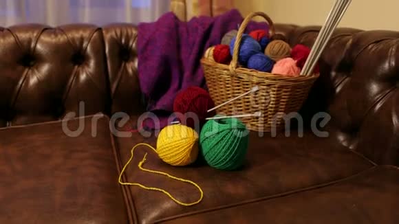许多五颜六色的羊毛纱躺在一张皮沙发上的柳条篮子里视频的预览图