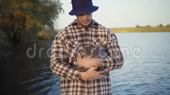 年轻人在湖边的大自然上抚摸一只猫视频的预览图