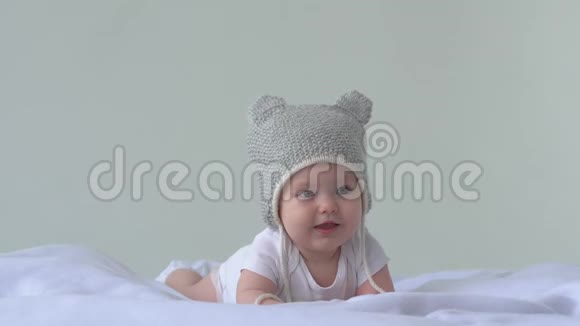 快乐的宝贝女儿戴帽子的孩子躺在床上笑白色背景视频的预览图