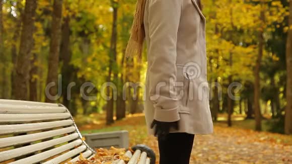 穿灰色外套和围巾的女人她坐在长凳上等人视频的预览图