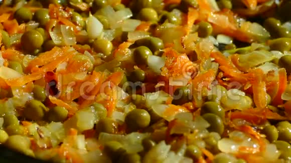 在煎锅里用洋葱和胡萝卜炒在煎锅中加入青和冷冻红辣椒视频的预览图