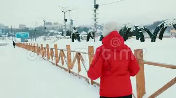 穿着红色夹克跑过马路的漂亮女人冬天视频的预览图