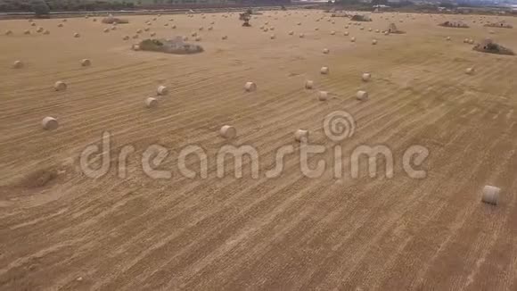 用干草球和石头建筑对收获的麦田进行空中飞行视频的预览图