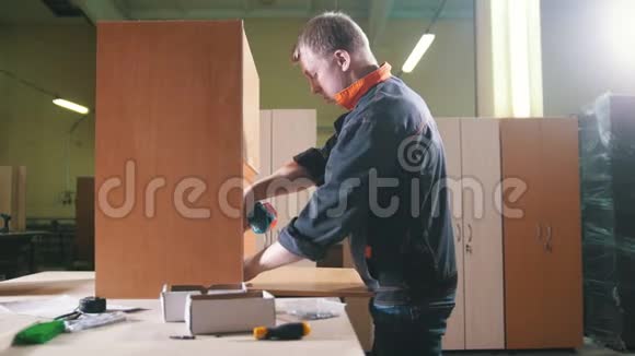 木匠用电动螺丝刀在工厂工作固定家具细节视频的预览图