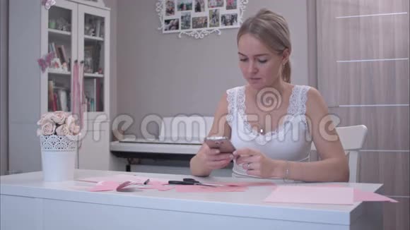 年轻女子一边用手机剪纸蝴蝶视频的预览图
