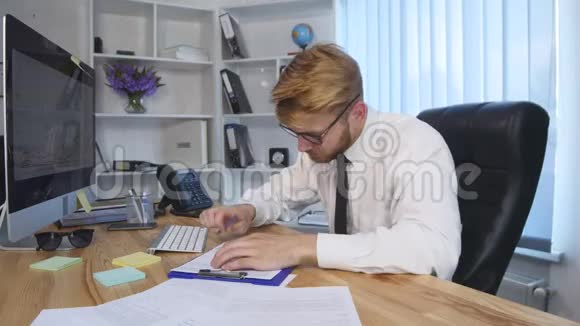 年轻的商人在电脑上工作在办公室的笔记本上做笔记视频的预览图