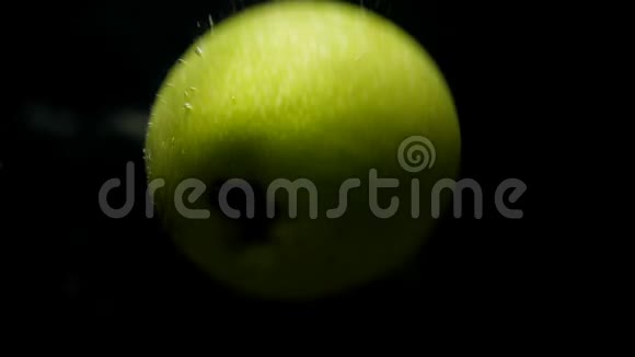 绿色苹果在黑色背景下以超慢的运动落在水中视频的预览图