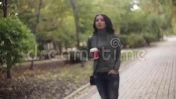 伤心的漂亮女孩走在公园里喝咖啡视频的预览图