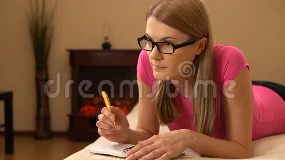 美丽迷人的年轻女子在笔记本上写作列个单子想着又笑视频的预览图