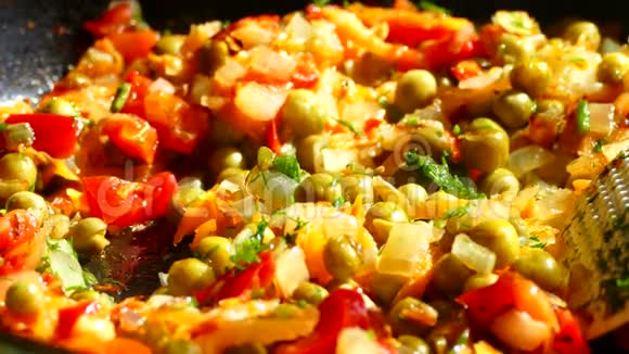 在煎锅里用洋葱和胡萝卜炒在煎锅中加入青和冷冻红辣椒视频的预览图