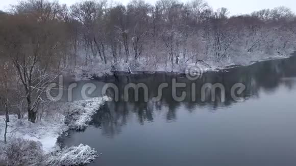 沿着河岸和被雪覆盖的森林飞行视频的预览图