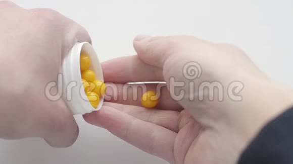 男人手里拿着一个白色聚合物药罐白色背景上有黄色维生素一个人视频的预览图