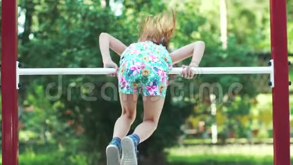小有趣的女孩倒挂在水平杆上慢动作视频的预览图