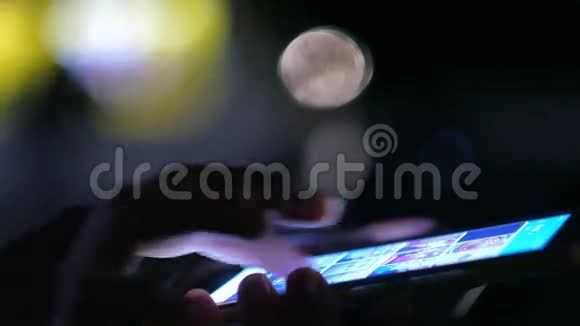 夜间妇女通过智能手机显示触摸屏视频的预览图