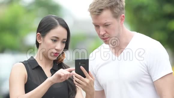 年轻的多种族夫妇在户外的街道上一起使用电话视频的预览图