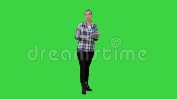 年轻女性使用阅读演示从平板电脑上的绿色屏幕铬键视频的预览图
