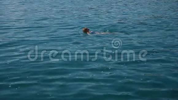 金发美女在开阔的大海里享受着水漂浮着从上面看慢动作视频的预览图