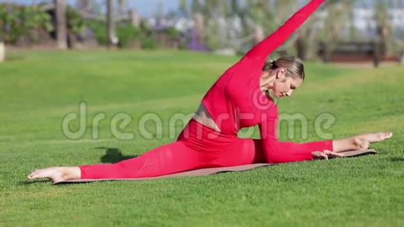 穿着红色乳胶服装的金发女郎正在做瑜伽练习视频的预览图