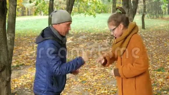 女儿和父亲在秋天公园玩剪刀纸石头两人都笑是因为他的家人很开心视频的预览图