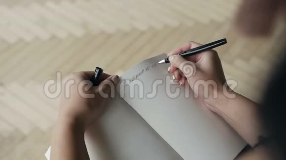 一位年轻女子在笔记本上用黑色钢笔写纸条视频的预览图