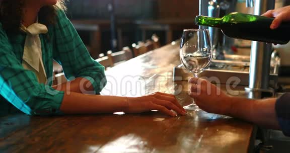 酒吧服务员为酒吧柜台的女顾客提供红酒视频的预览图