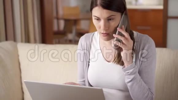 女商人坐在家里手提电脑和智能手机通过手机在屏幕上讨论项目视频的预览图