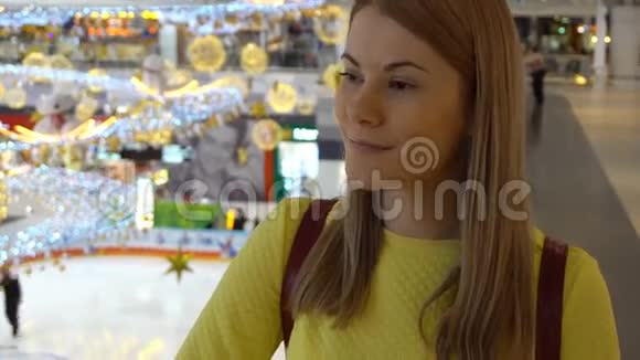 年轻漂亮的女人穿着一件黄色的衬衫在商场里圣诞节新年装饰视频的预览图