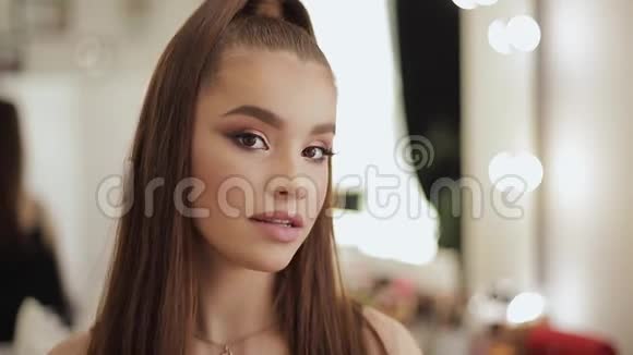 年轻漂亮的模特化妆后照镜子漂亮的年轻女子坐在美容室里视频的预览图