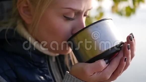 金发女郎正在喝热水瓶里的茶视频的预览图