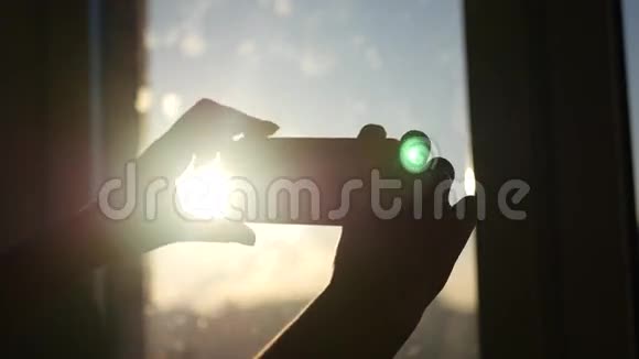 女孩在靠近窗户的手机上拍了一张日落照片动作缓慢视频的预览图