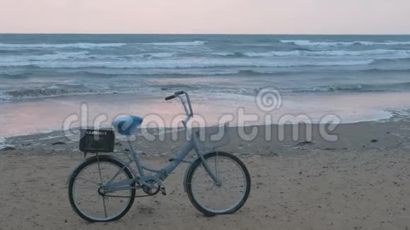 日落时海滩上的旧自行车有风暴海和泡沫波的背景视频的预览图