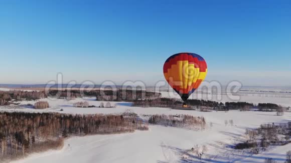 空中拍摄的人们乘坐一个大明亮的气球飞越冬季森林视频的预览图