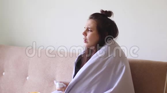 生病的年轻妇女坐在家里流鼻涕打喷嚏视频的预览图