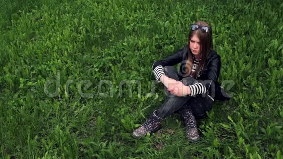 坐在草地上微笑的年轻女孩的视频画像视频的预览图