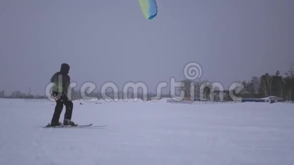 一个年轻人抓住了风筝的风他被拉到了雪地上视频的预览图