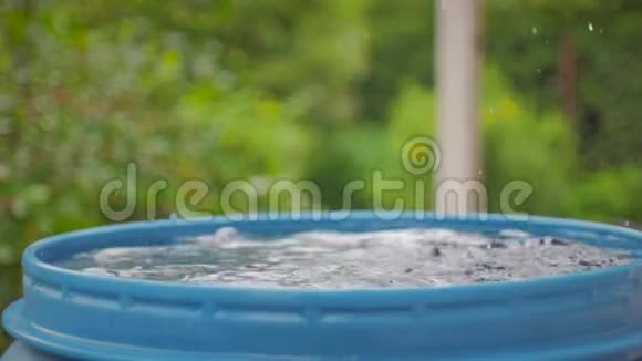 屋顶上的水滴掉进了一个蓝色的桶里视频的预览图