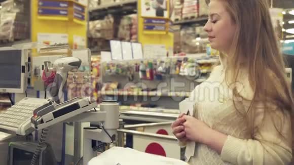 在超市的收银台买塑料卡的年轻女性股票录像视频的预览图