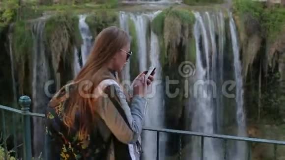 美丽开朗快乐年轻的金发女孩在一个大女孩的背景下写一条信息用智能手机视频的预览图