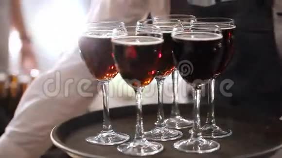 托盘上的红酒服务员给客人端着带有红酒的酒杯酒杯里的红酒视频的预览图